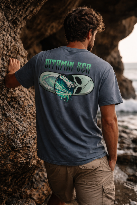 Man wearing a t-shirt with a graphic design standing near a rocky cave entrance.